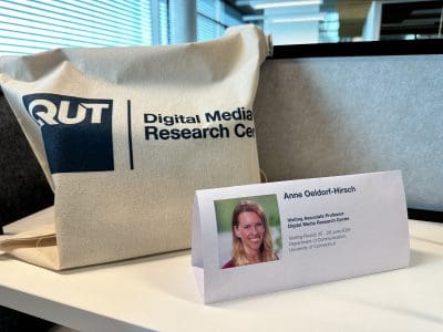 Picture of name tag and QUT DMRC tote bag on desk.